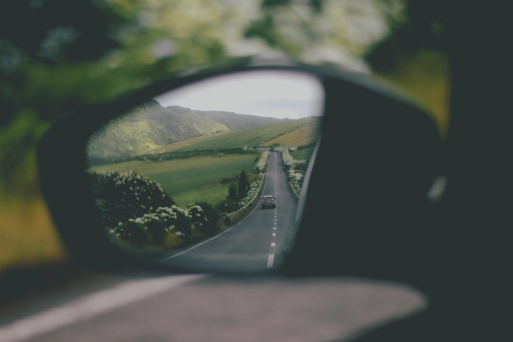 une route boisée dans le reflet d'un rétroviseur de voiture