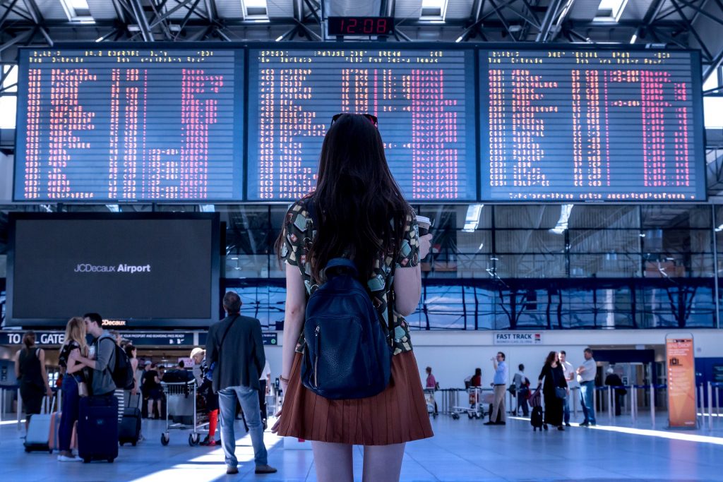 Femme de dos regardant un panneau de départs d'avions