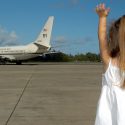 une petite fille saluant un avion sur une piste