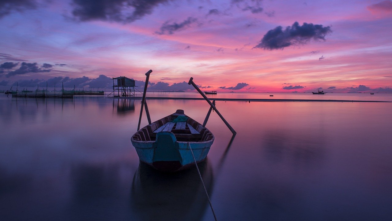 vacances dernière minute, bateau sur l'eau avec coucher de soleil